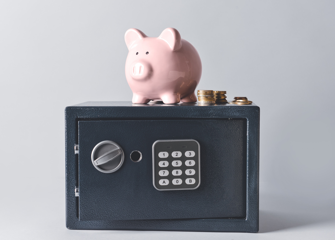 Piggy Bank and Coins on a Modern Safe Box