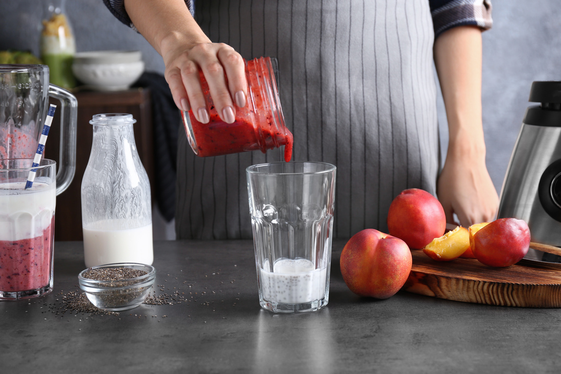 Young Woman Preparing Smoothie with Chia Seeds on Table